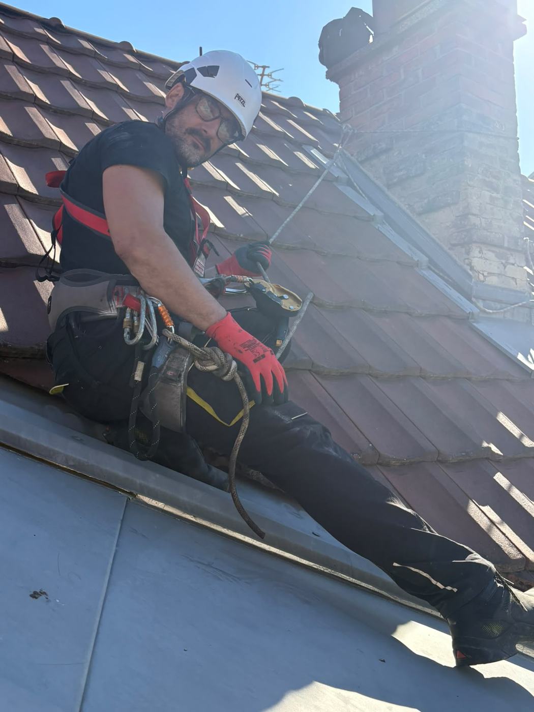 Technicien encordé sur un toit en tuiles